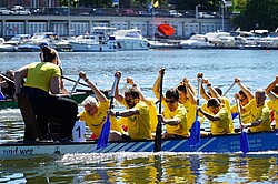 Mannschaft in gelben Trikots in einem blauem Drachenboot.