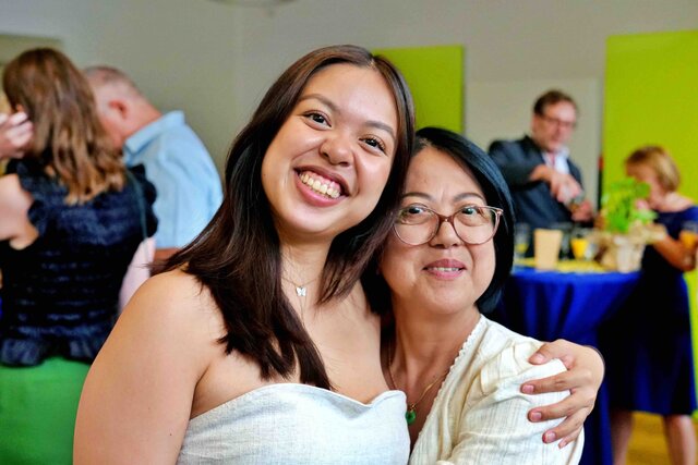 Zu sehen sind Frauen beim Sektempfang, die sich umarmen und in die Kamera lachen.