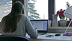 Das Bild zeigt eine Studierende an einem Schreibtisch