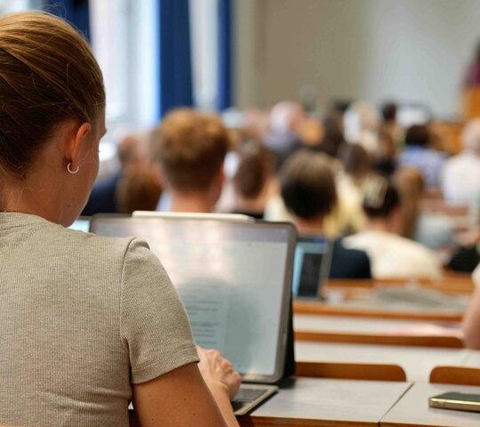 Eine Studierende sitz im Hörsaal während einer Vorlesung. 