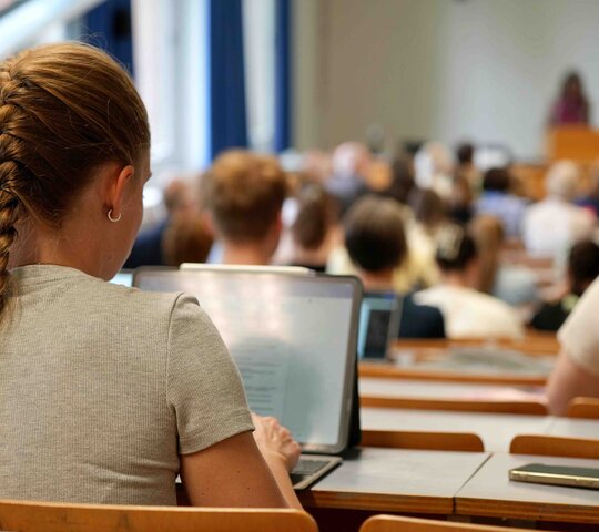 Eine Studierende sitz im Hörsaal während einer Vorlesung. 