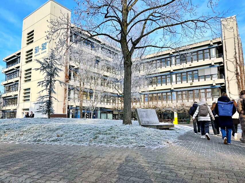 Der Neubau der Pädagogischen Hochschule im Winter. Es liegt Schnee. Eine Gruppe von Menschen, die warm angezogen sind, geht auf das Gebäude zu.