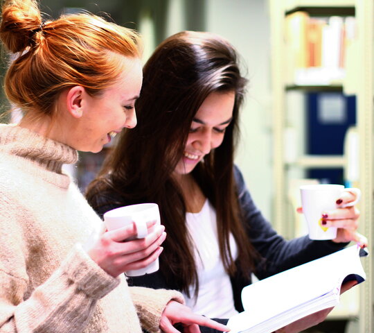 Das Bild zeigt zwei Studierende in der Bibliothek