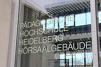 Scheibe mit der Aufschrift " Pädagogische Hochschule Heidelberg Hörsaalgebäude".
