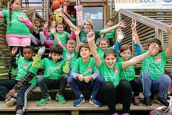 verschiedene Kinder auf einer Treppe sitzend, die alle ein grünes T-Shirt tragen. Copyright Climb 