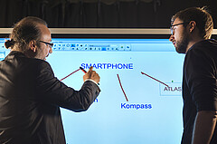 Das Foto zeigt zwei Männer vor einem Whiteboard.
