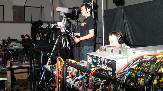Ein Kameramann und ein Techniker hinter der Aufzeichnungsanlage bei einer Theaterproduktion.