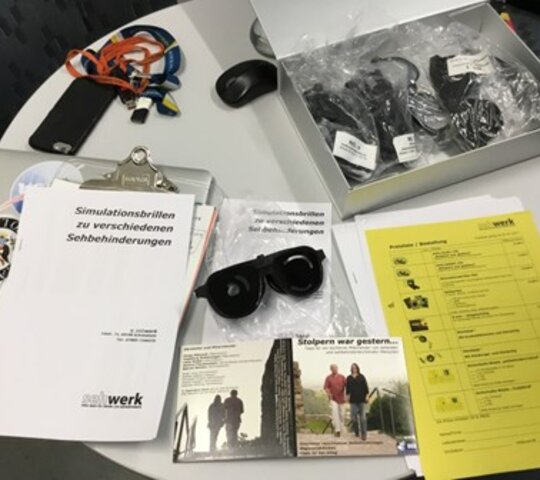 Verschiedene Materialen zur Simulation von Sehbehinderung liegen auf einem Tisch.