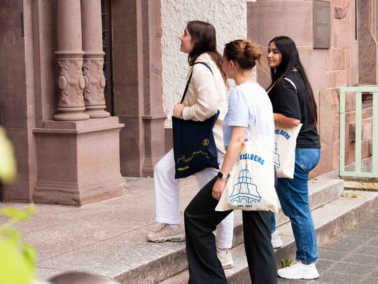 Drei Frauen gehen auf das Hauptportal der Hochschule zu. 