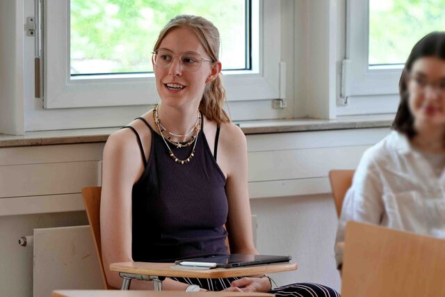Eine Studentin sitzt an einem Tisch im Seminarraum. 