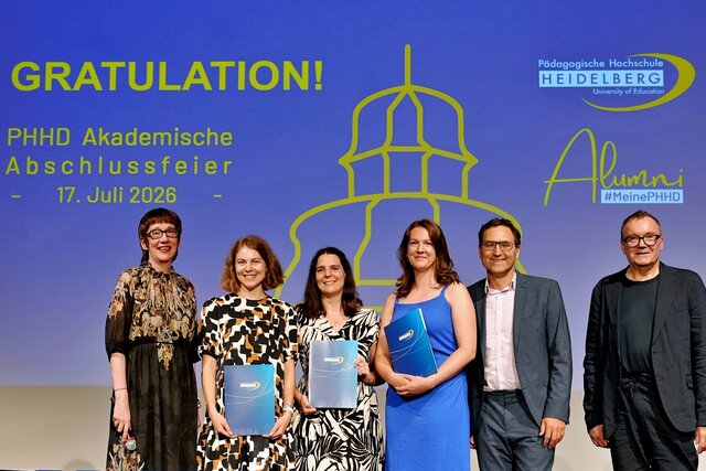 Zu sehen sind Absolvent:innen der PHHD, die sich mit ihren Urkundenmappen auf der Bühne zum Gruppenfoto aufgestellt haben.