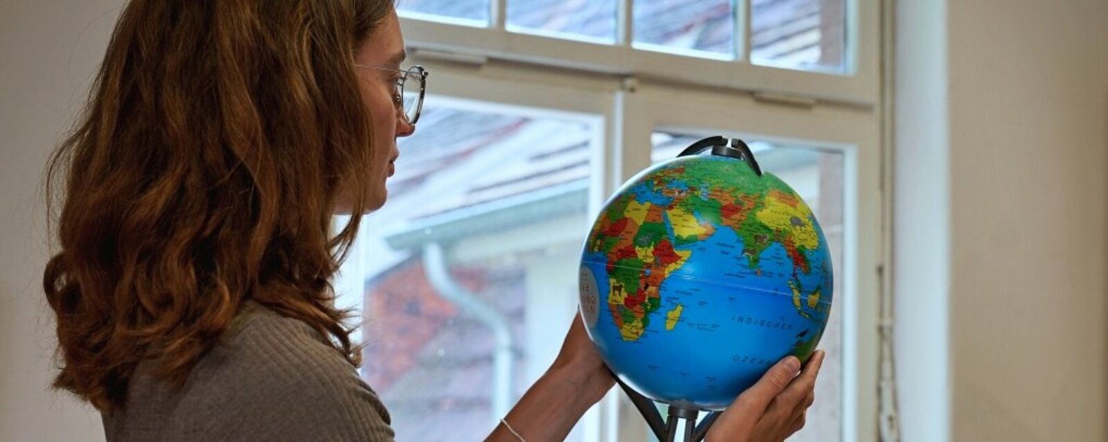 Eine Studentin steht in einem Raum der Pädagogischen Hochschule und sucht auf einem Globus die Länder der internationalen Hochschulpartner der PH.