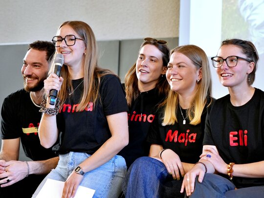 5 Mitglieder des studentischen BeTa-Teams sitzen mit einem Mikrofon auf der Bühne