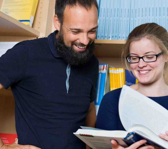 Ein Mann und eine Frau blättern gemeinsam in einem Buch. 