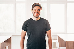 Die Porträtaufnahme zeigt Max Wetterauer. Er steht im Transferzentrum der Hochschule und lächelt direkt in die Kamera.