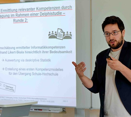 Ein Mann steht vor einem Forschungsplakat und präsentiert.