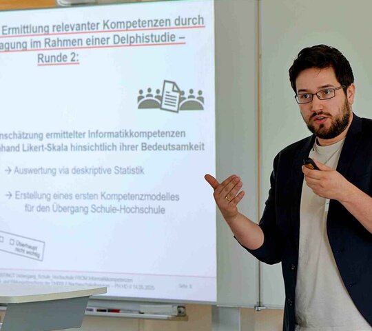 Ein Mann steht vor einem Forschungsplakat und präsentiert.