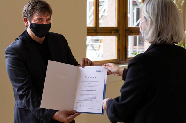 Mario Urlaß trägt corona-bedingt Maske und empfängt seine Urkunde von Vera Heyl.