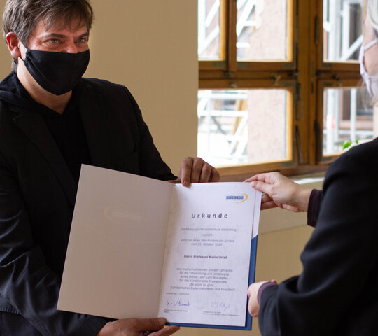 Mario Urlaß trägt corona-bedingt Maske und empfängt seine Urkunde von Vera Heyl.