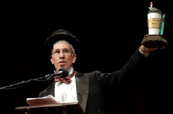 Das Foto zeigt wie Moderator Marc Abrahams den Ig-Nobelpreis hält.