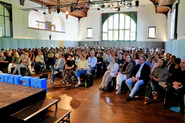 Zu sehen ist das sitzende Publikum in der Festhalle.