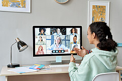 Das Symbolbild zeigt eine Schülerin vor dem PC. Auf diesem ist ein Online-Unterricht zu sehen.