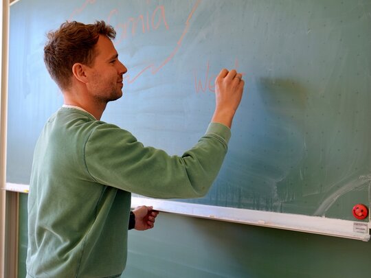 Ein Lehrer schreibt an eine Tafel.