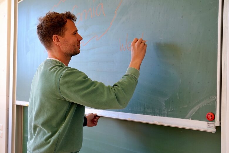 Ein Lehrer schreibt an eine Tafel.