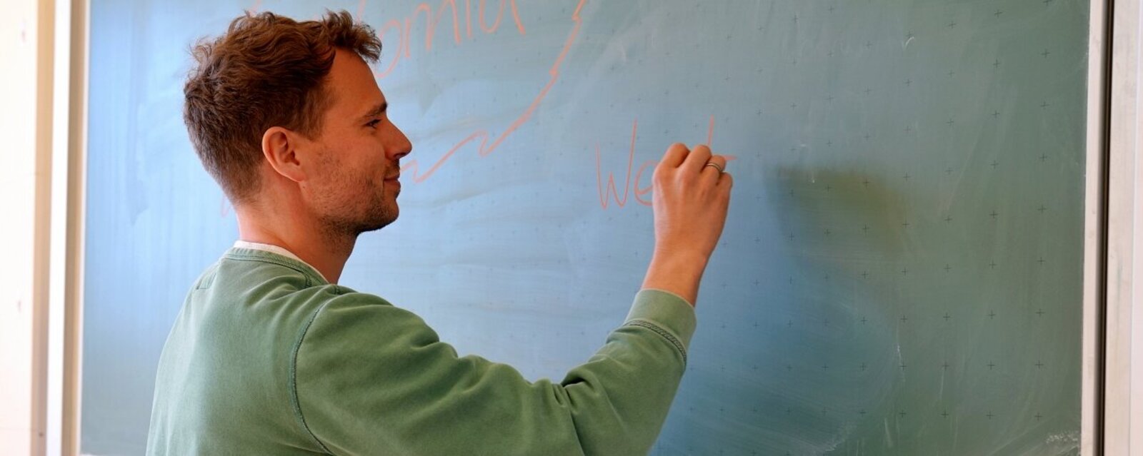 Ein Lehrer schreibt an eine Tafel.