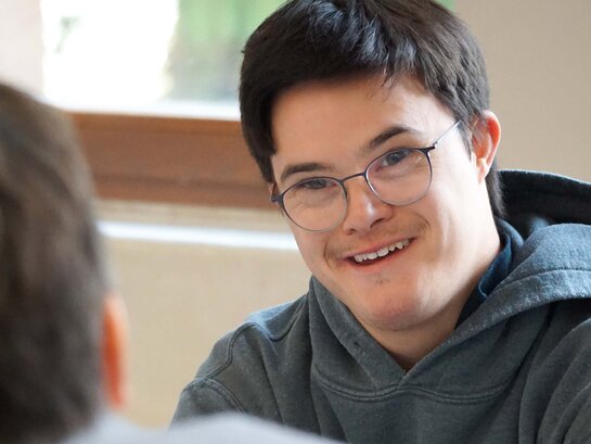 Das Foto zeigt eine Person von der Seite in einem Gespräch.