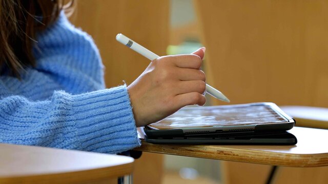 Studentin schreibt auf Tablet