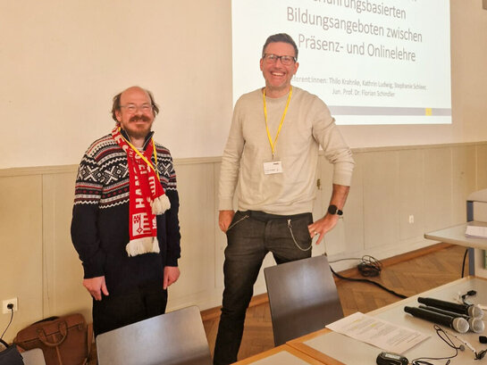 Thilo Krahnke und Florian Schindler stehen in der Aula vor der Beamer-Leinwand.