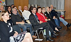 Das Foto zeigt Menschen in Stuhlreihen in der Aula.