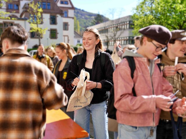 Zu sehen ist eine Studentin in Mitten einer Menschenmenge 