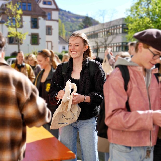 Zu sehen ist eine Studentin in Mitten einer Menschenmenge 