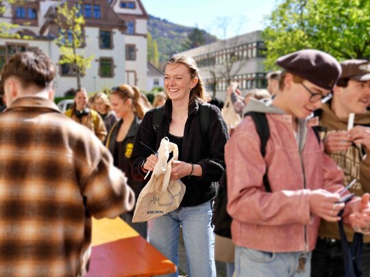 Zu sehen ist eine Studentin in Mitten einer Menschenmenge 