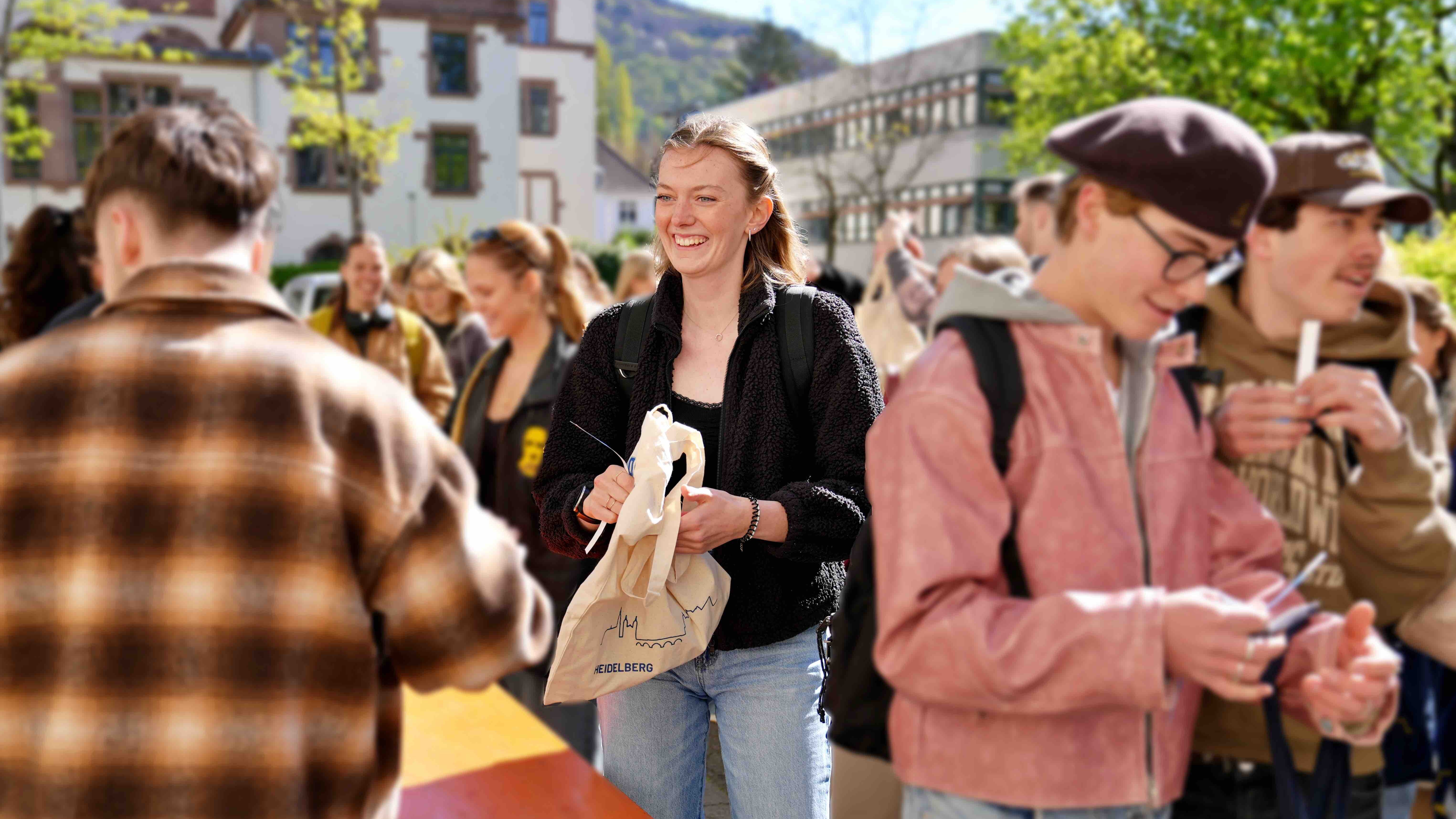 Zu sehen ist eine Studentin in Mitten einer Menschenmenge 