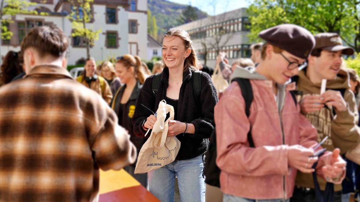 Zu sehen ist eine Studentin in Mitten einer Menschenmenge 