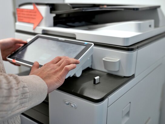 Das Foto zeigt einen Drucker mit einer Hand.