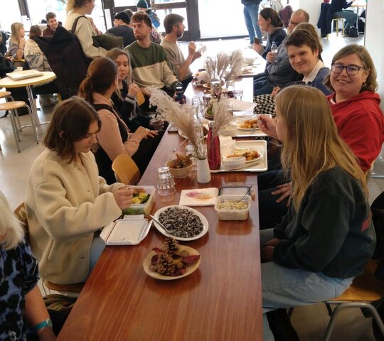 Mitarbeitende und Studierende der PH Heidelberg sitzen am PHeelGood-Tisch und unterhalten sich.