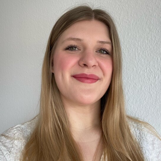 Man sieht Svenja im Portait-Format. Sie trägt die blonden langen Haare offen und lächelt in die Kamera.