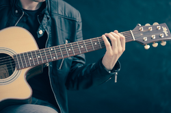 Das Foto zeigt einen Teil eines Mannes der Gitarre spielt.