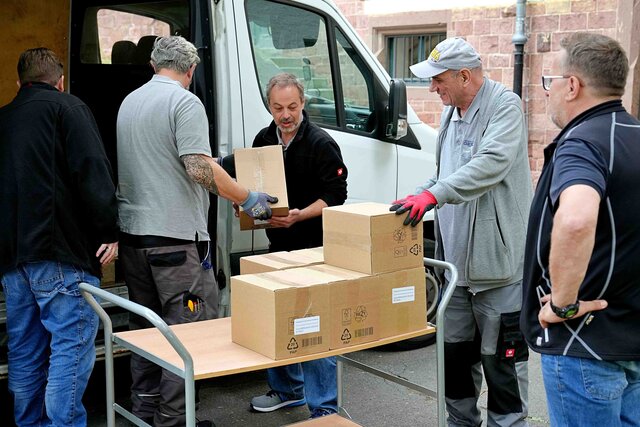 Kollegen der Verwaltung helfen einer zentralen Einrichtung mit dem Einladen von Kartons.