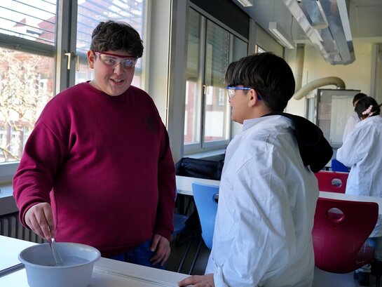 Das Foto zeigt zwei Schüler im Chemieunterricht beim Experimentieren.