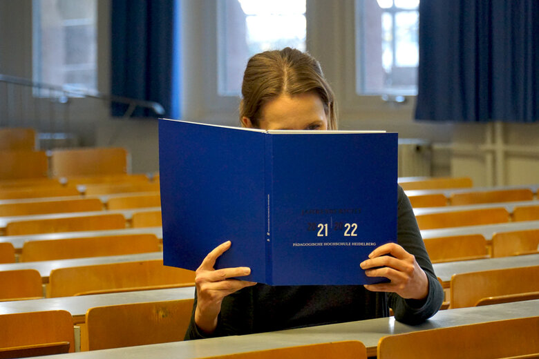 Frau sitzt in einem Hörsaal der Hochschule. Sie liest die 2021-2022-Ausgabe des Jahresberichts.