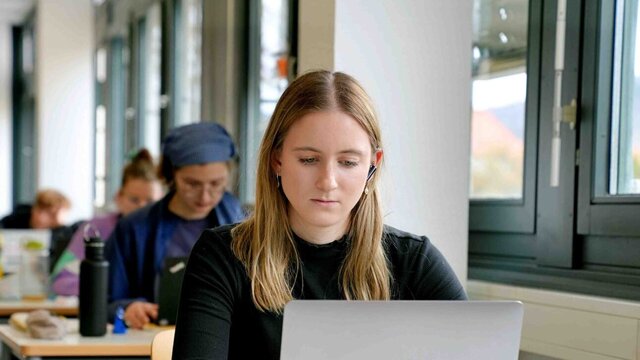 Zu sehen ist eine NLS-Studentin am Schreibtisch.