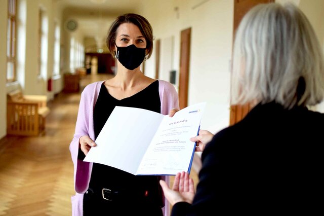 Nicola Kluß trägt corona-bedingt eine Maske und empfängt ihre Urkunde von Vera Heyl