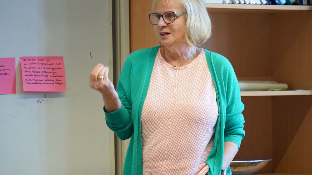 Manuela Welzel-Breuer steht vor einer Pinnwand und redet deutlich mit den Händen.