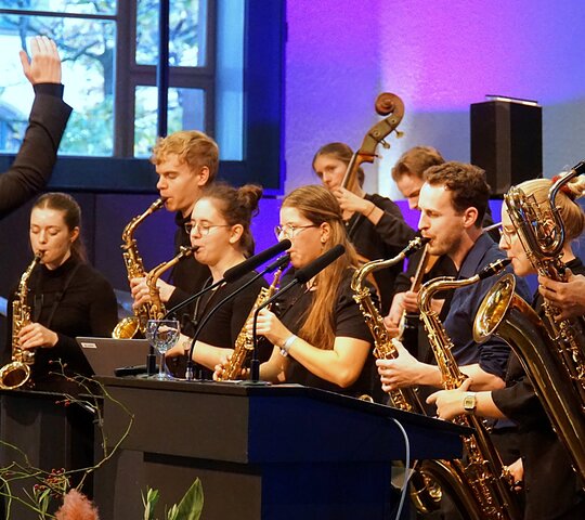 Zu sehen ist ein Orchester mit Dirigenten. 