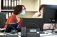 Das foto zeigt zwei Mitarbeitende der AW-ZIB sitzend am Schreibtisch vor ihren Monitoren.